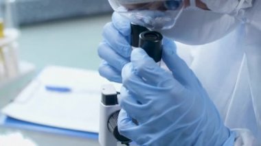 Mikroskoba bakarken not alan laboratuvar teknisyeninin el çekimini kapatın