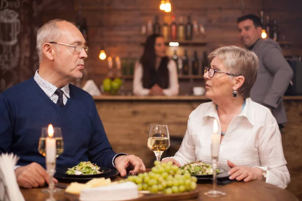 Ältere Schwester erzählt ihrem kleinen Bruder, was in letzter Zeit beim Abendessen in einem gemütlichen Restaurant los war — Stockfoto