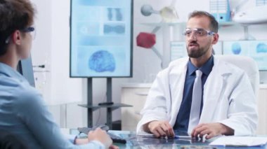 Hastaya bir şeyler gösteren artırılmış gerçeklik gözlüğü takan doktor
