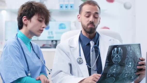 Medical scientist with a nurse in modern office looking at MRI and CT scans — Stock Video