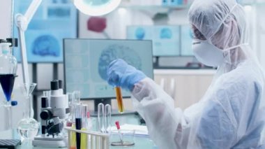 Örnek tüplerle çalışan beyaz tulumlu ve koruyucu gözlüklü bilim adamı