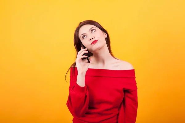 Yelloq arka plan üzerinden telefonda konuşurken sıkılmış güzel genç kadın Portresi — Stok fotoğraf