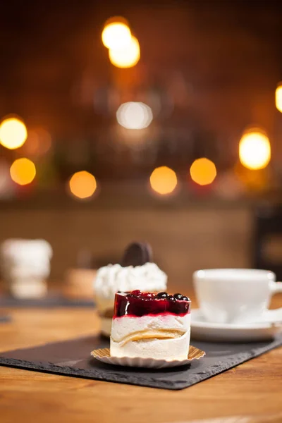 Close-up van smakelijke mini-cake met fruit bovenop een houten tafel in een koffieshop — Stockfoto