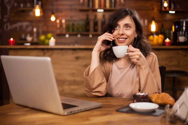 커피를 마시고 현대적인 커피 숍에서 전화를 받는 젊은 비즈니스 여성 — 스톡 사진