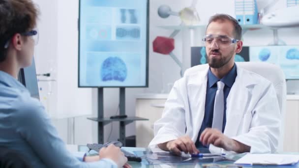 Doctor con gafas AR mostrando algo a un paciente — Vídeos de Stock