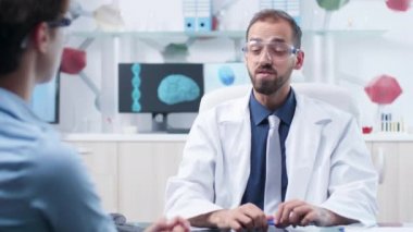 AR gözlüklü Kafkas doktoru bir hastaya bir şey gösteriyor