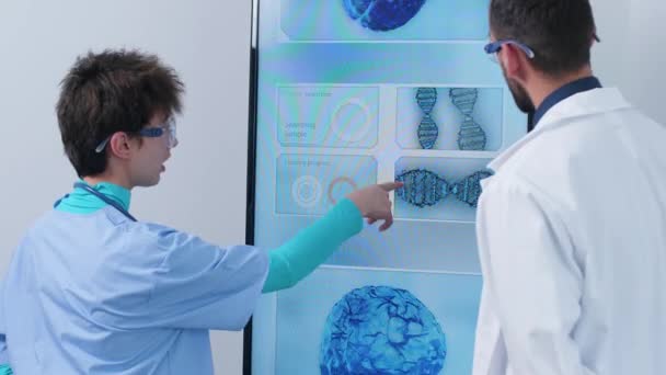 3D脳シミュレーションを分析する大画面ディスプレイの前で看護師と医師のハンドヘルドショット — ストック動画