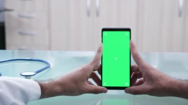 Yeşil ekran ile bir akıllı telefon tutan erkek elleri çekim yakın