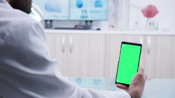 Zoom em tiro em mãos de médico segurando um smartphone com tela verde — Vídeo de Stock