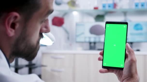 Arzt schaut auf Handy mit grünem Bildschirm — Stockvideo