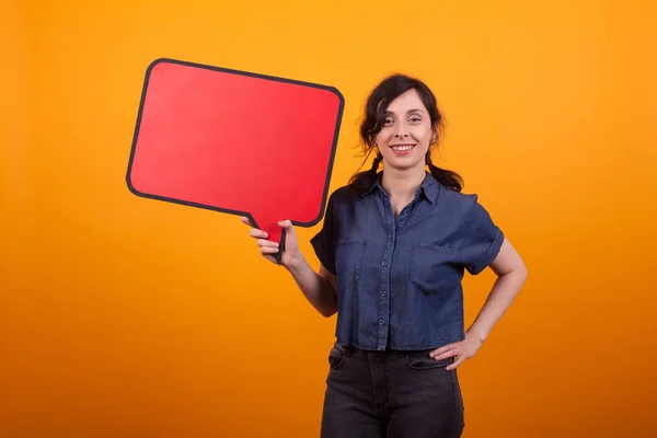 Portret van jonge vrouw Holding Red thought Bubble over gele achtergrond in Studio — Stockfoto