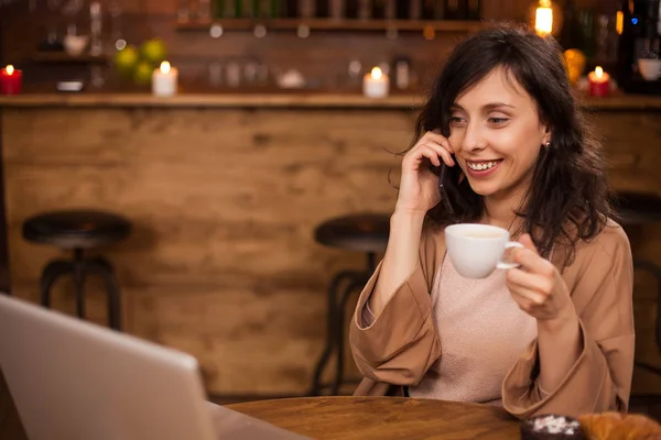 Veselá obchodní žena se usmíjí a dívá se na svůj notebook v kavárně — Stock fotografie