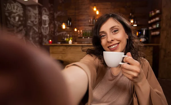 Schöne Frau mit Handy, um ein Selfie während ihrer Arbeit in einem Café zu machen — Stockfoto