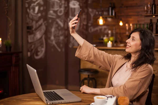 Hübsches junges Mädchen beim Selfie mit ihrem Handy in einem modernen Café — Stockfoto