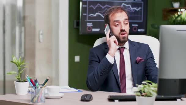 In einem kreativen Büro hat ein junger Geschäftsmann ein Gespräch mit einem anderen am Telefon — Stockvideo