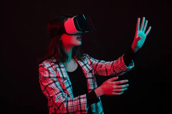 Chica joven con gafas de realidad virtual auriculares en el estudio con iluminación de colores — Foto de Stock