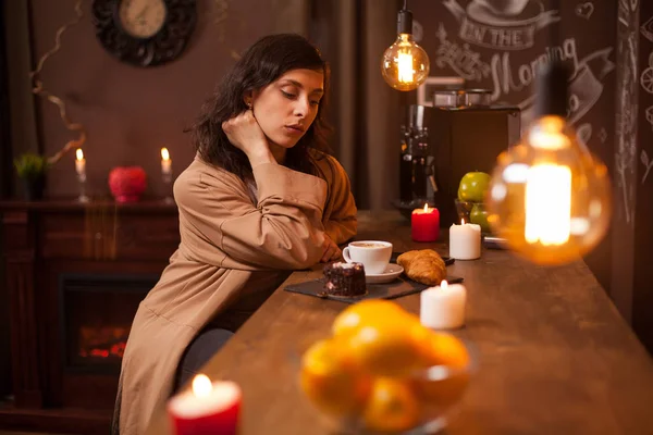 Beleza jovem morena sentada no bar com uma xícara de café e bolo saboroso no café de luxo — Fotografia de Stock