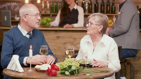 Old couple sitting at the table in a restaurant and drinking wine