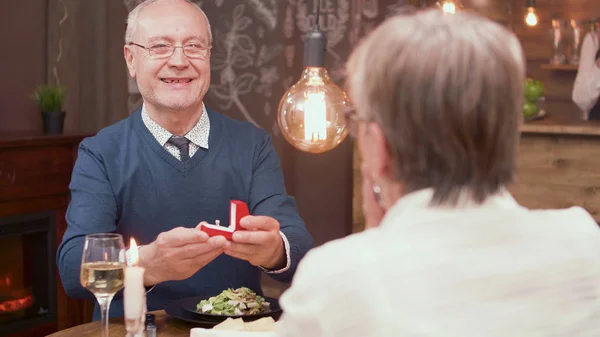 Милый старик подарил своей жене красивое кольцо в красной коробке за ужином — стоковое фото
