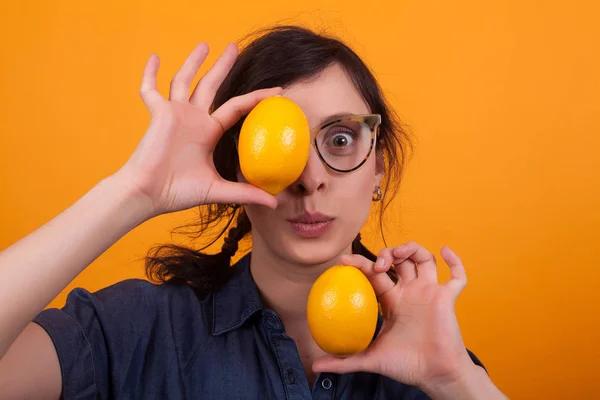 Retrato de mujer hermosa sorprendida con dos sabrosas naranjas como ojos sobre fondo amarillo —  Fotos de Stock