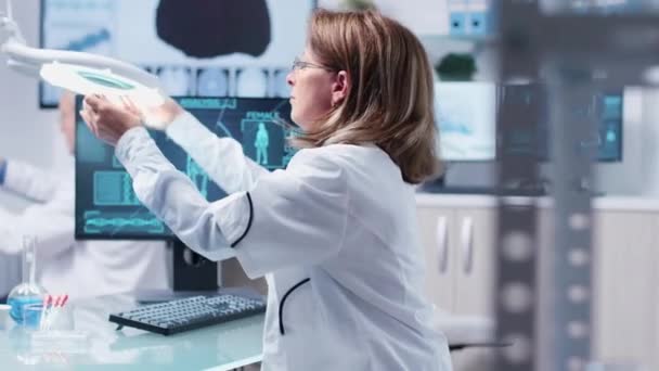 Female scientist uses a magnifying glass in modern laboratory — Stock Video