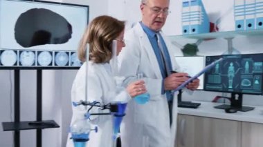 Modern laboratuvarda yürürken konuşan olgun bilim adamlarından oluşan ekip