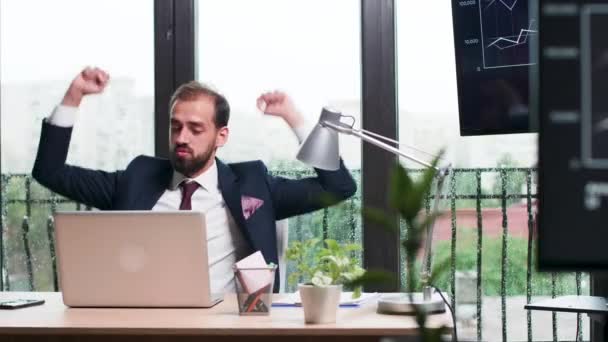 Бизнесмен счастливо танцует за своим столом — стоковое видео