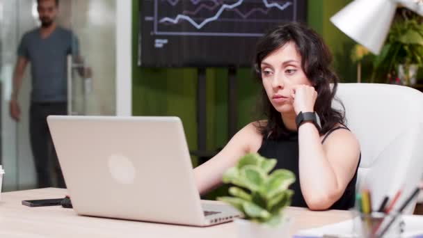 Gerente senta-se no computador, olha para o relógio e percebe que ela está atrasada para uma reunião — Vídeo de Stock