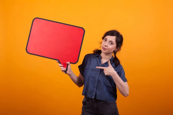 Portret van vrolijke jonge vrouw wijzend op virtueel dialoogvenster in Studio over gele achtergrond — Stockfoto