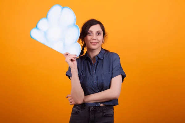 Atractiva mujer joven sosteniendo una nube de ideas en el estudio sobre fondo amarillo — Foto de Stock