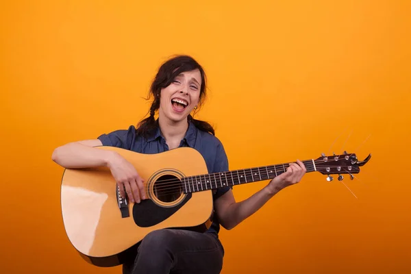 Portrait jeune chanteur avec guitare acoustique en studio sur fond jaune — Photo