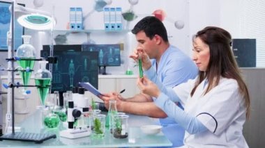 Asistanıyla birlikte bilim adamları test örneklerine yeşil sıvıyla bakıyorlar.