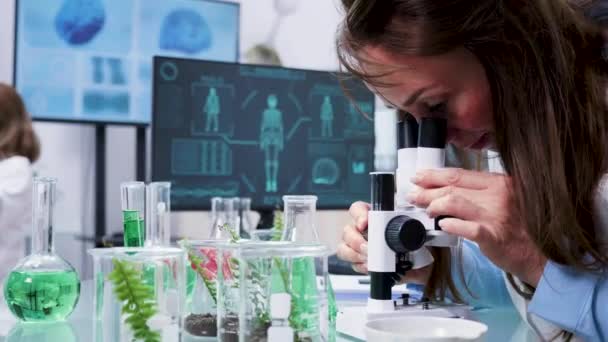 Gros plan de la biologiste féminine regardant au microscope — Video