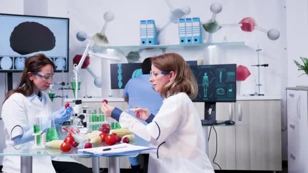 Pesquisadora feminina injetando amostras de OGM em morangos — Vídeo de Stock