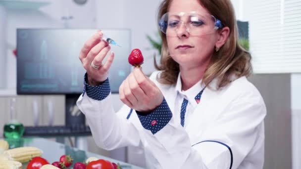 Zoom in close up shot van wetenschapper injecteren van GGO-monsters in aardbeien — Stockvideo