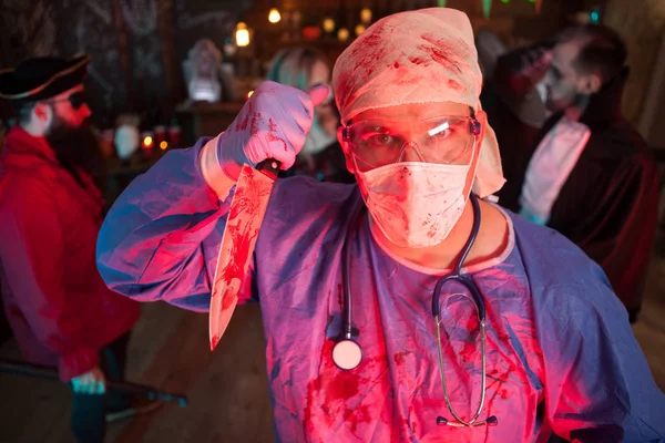 Attraente giovane uomo in un costume medico che tiene un coltello alla festa di Halloween — Foto Stock