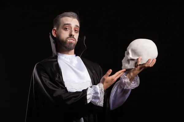 Homme attrayant en costume de Dracula et théet vampire tenant un crâne humain — Photo