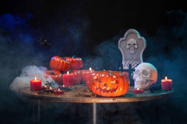 Turuncu kabak ahşap bir masada cadılar bayramı partisi için korkutucu yüzü ile oyulmuş