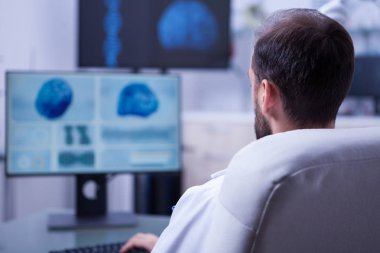 Genç sakallı doktor bilgisayar klavyesi bir hasta için bir tanı yazarak