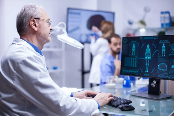 Esperto scienziato senior digitando i dati nel computer dall'ultimo esperimento sul corpo umano — Foto Stock