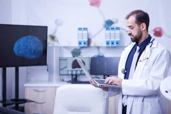 Side view portrait of young doctor with laptop in his hospital cabine — Stock Photo, Image