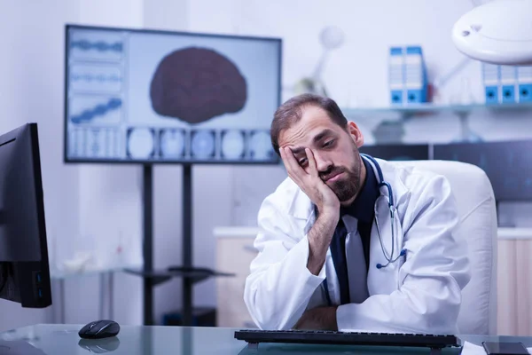 Портрет молодого и перегруженного работой врача с изображением мозга в больничном шкафу — стоковое фото