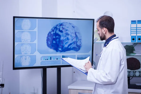 Doctor revisando los análisis cerebrales de un paciente en su portapapeles —  Fotos de Stock