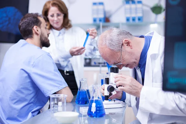 Cientista sênior fazendo testes ao microscópio em um laboratório moderno — Fotografia de Stock