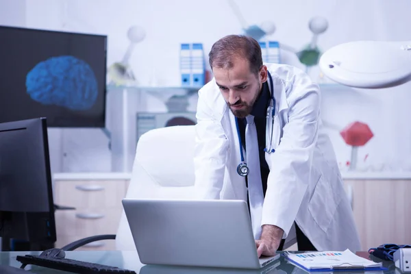 Läkare som arbetar på sin bärbara dator och kontrollera behandlingen av sina patienter — Stockfoto