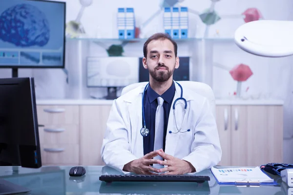 Retrato del médico guapo y confiado que mira confiado en la cámara en su gabinete —  Fotos de Stock