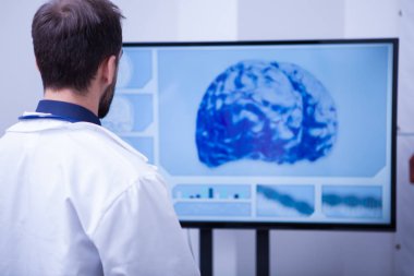 Hastanedeki erkek doktor monitördeki tomografi beynini araştırıyor