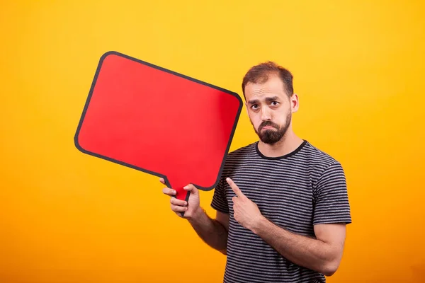 Portrait d'un jeune homme triste pointant son signe d'information sur fond jaune — Photo