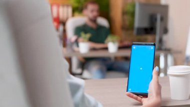 Kadın izole mavi ekran mock-up ile bir telefon tutar