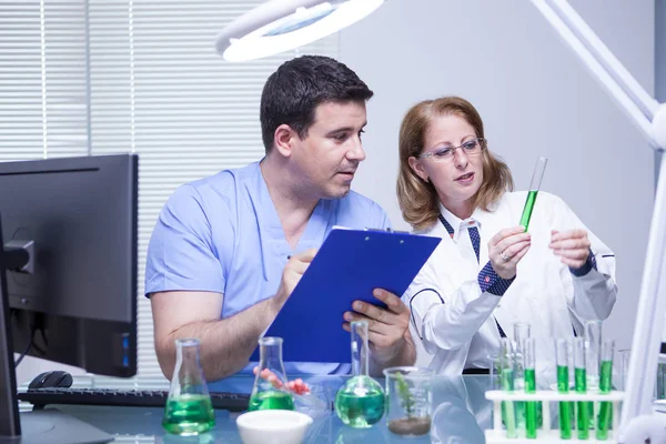 Científicos en biotecnología revisan la solución desde un tubo de ensayo — Foto de Stock
